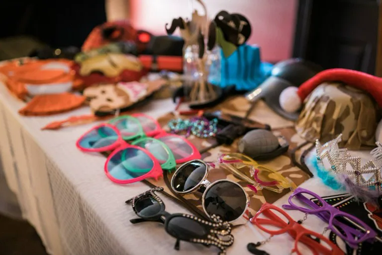 Photo booth props on a table, including sunglasses, hats and a crown