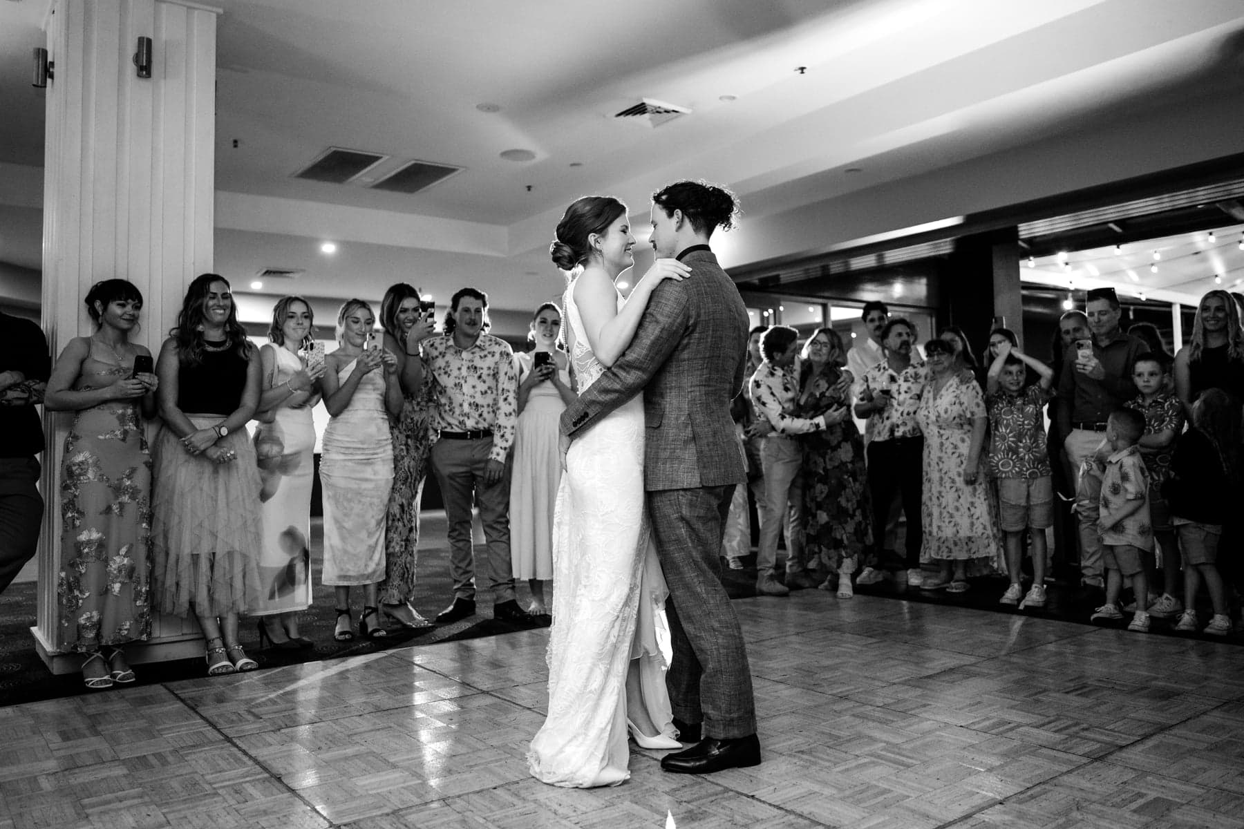 Jesse and Evie dancing together at The Sebel Kiama, surrounded by friends and family in a black-and-white photograph