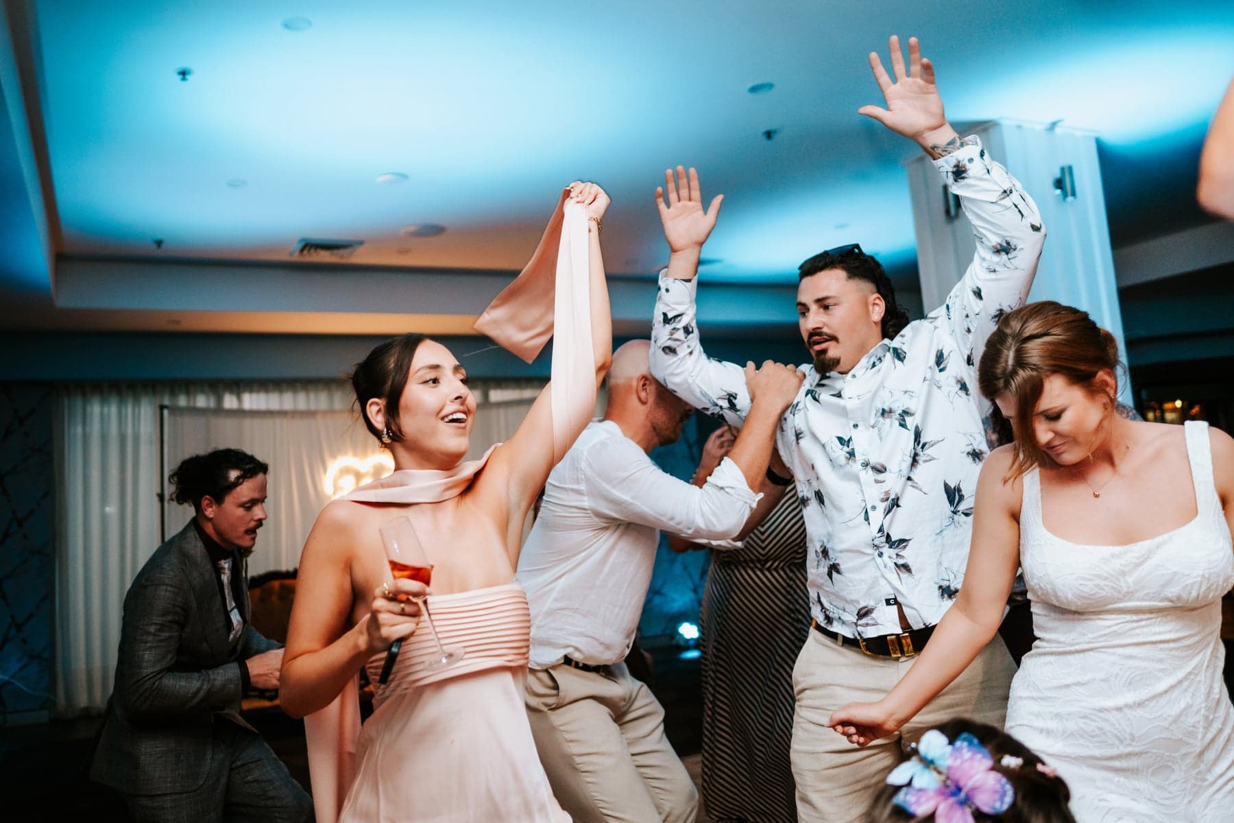 Jesse, Evie and their guests enjoying the dancefloor beneath blue reception lighting at The Sebel Kiama