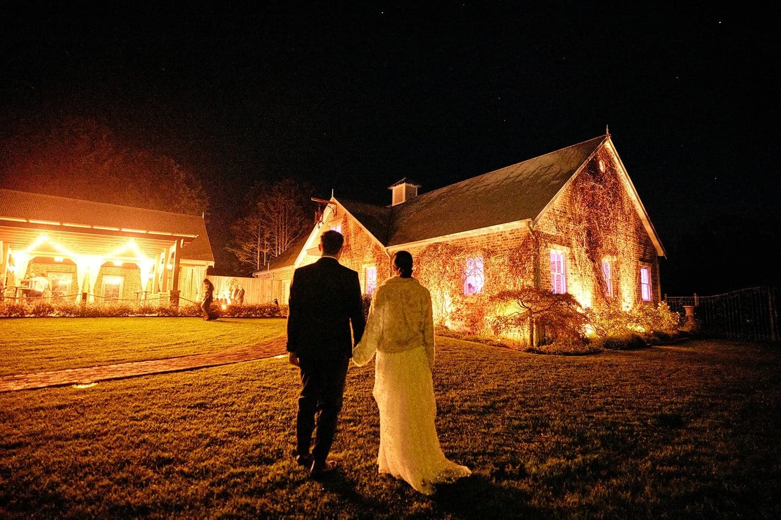 Phil and Caela outside Montrose House with the reception building lit up at night