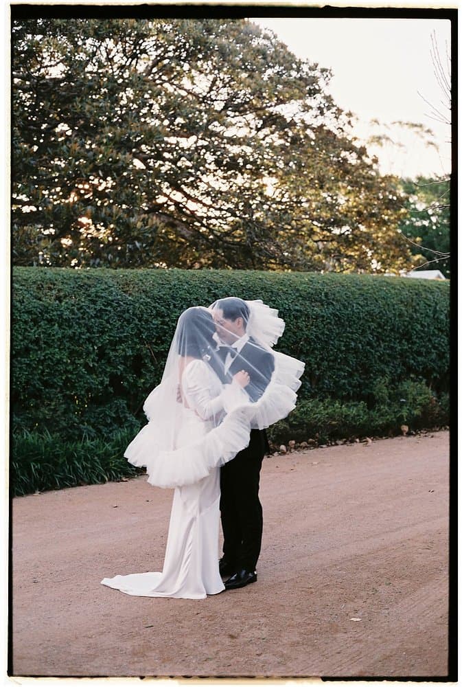 Sarah and Nathan sharing a kiss beneath her veil at Greyleigh