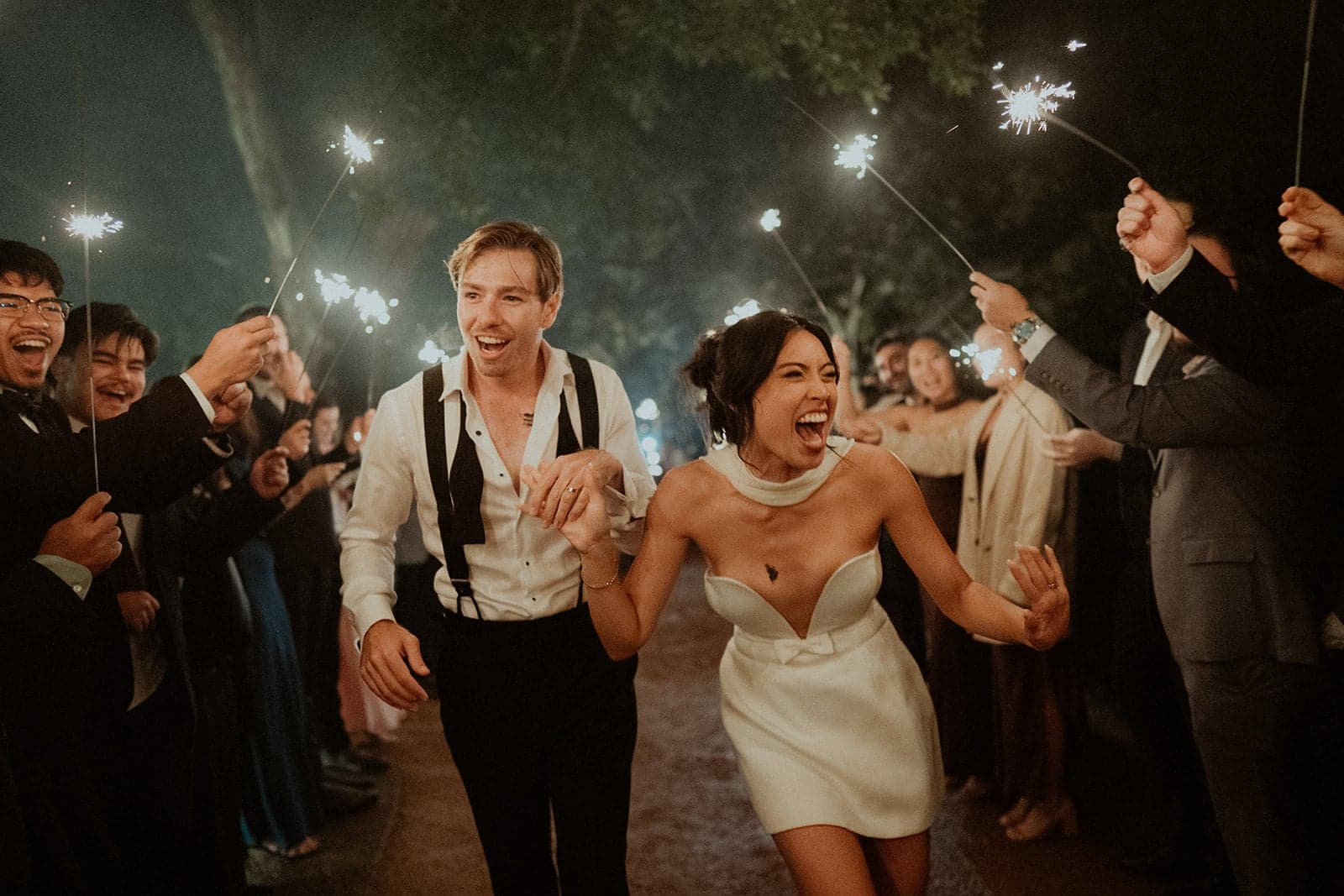 Stephanie and James celebrating outside with friends holding sparklers