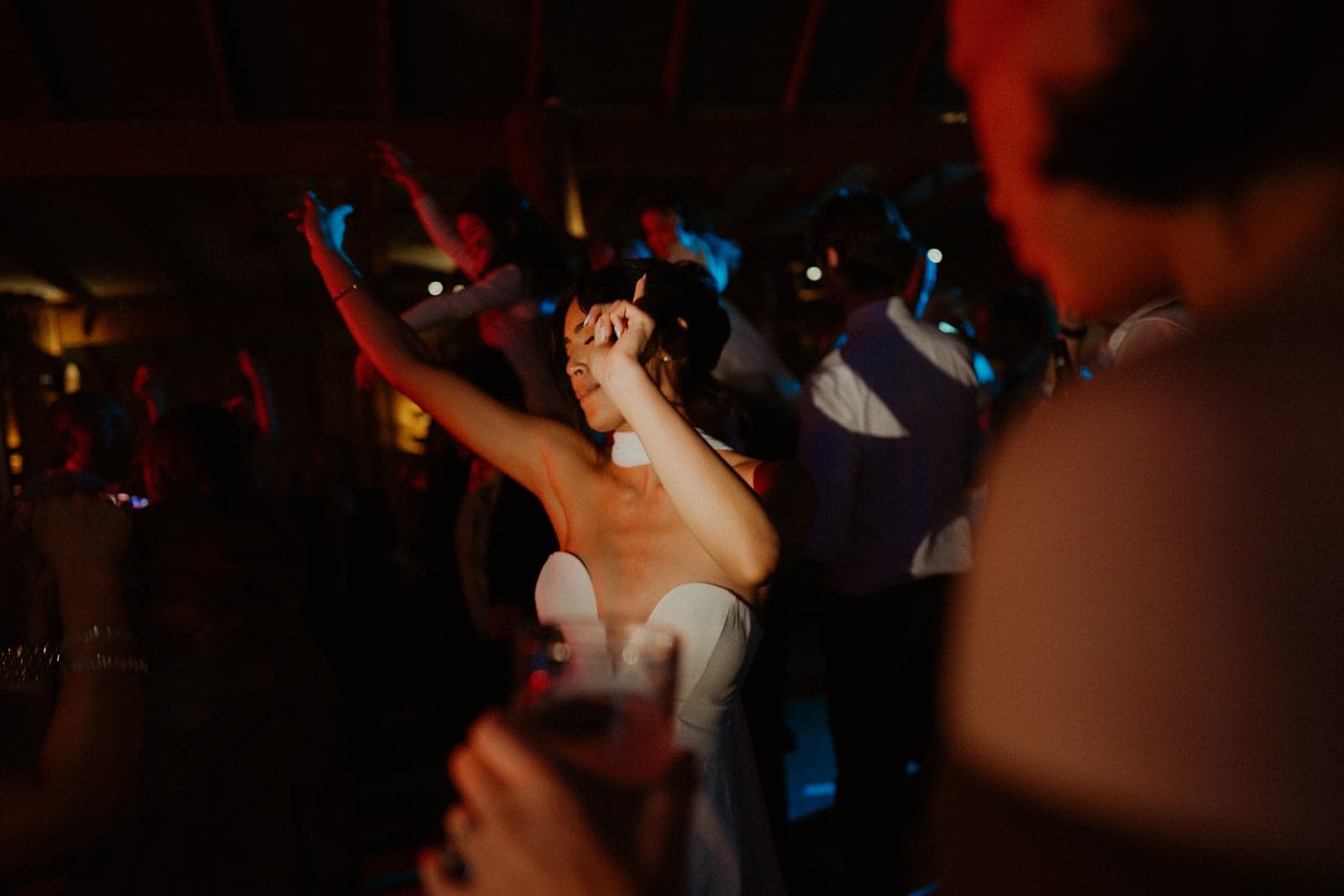 Stephanie celebrating with her hands in the air among wedding guests on the dancefloor